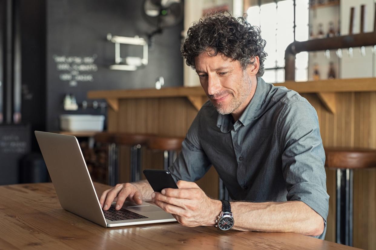 mature businessman working at cafe with laptop and mobile