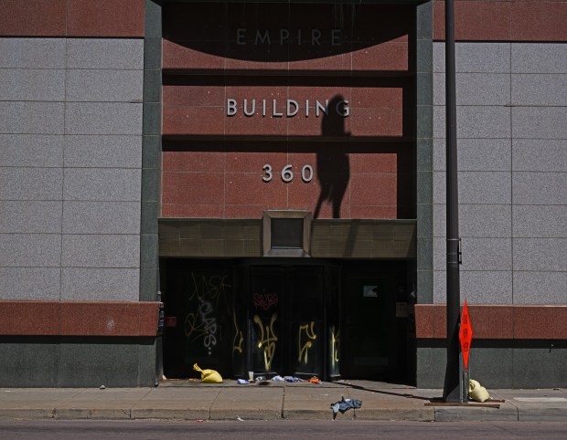 A vintage-looking gray and maroon building, with grafitti on the doors. The signage says, 'Empire Building 360.'