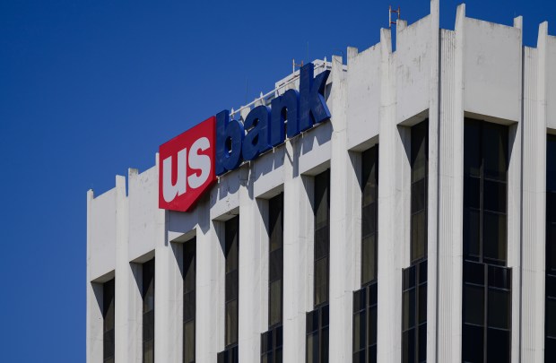 A vintage-looking building with a white exterior, recessed windows as a red, white and blue sign that says, 'us bank.'