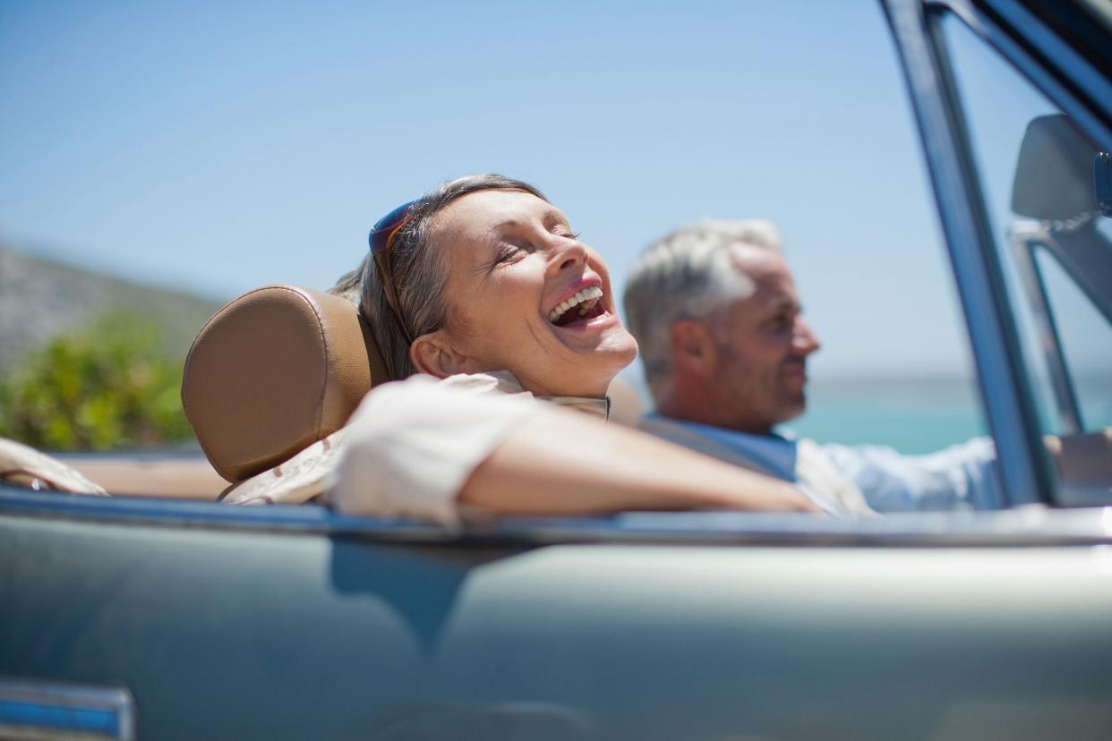 mature couple driving in convertible along the beach