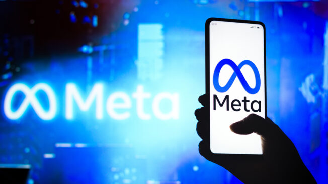 a hand holding a cellphone with the Meta logo
