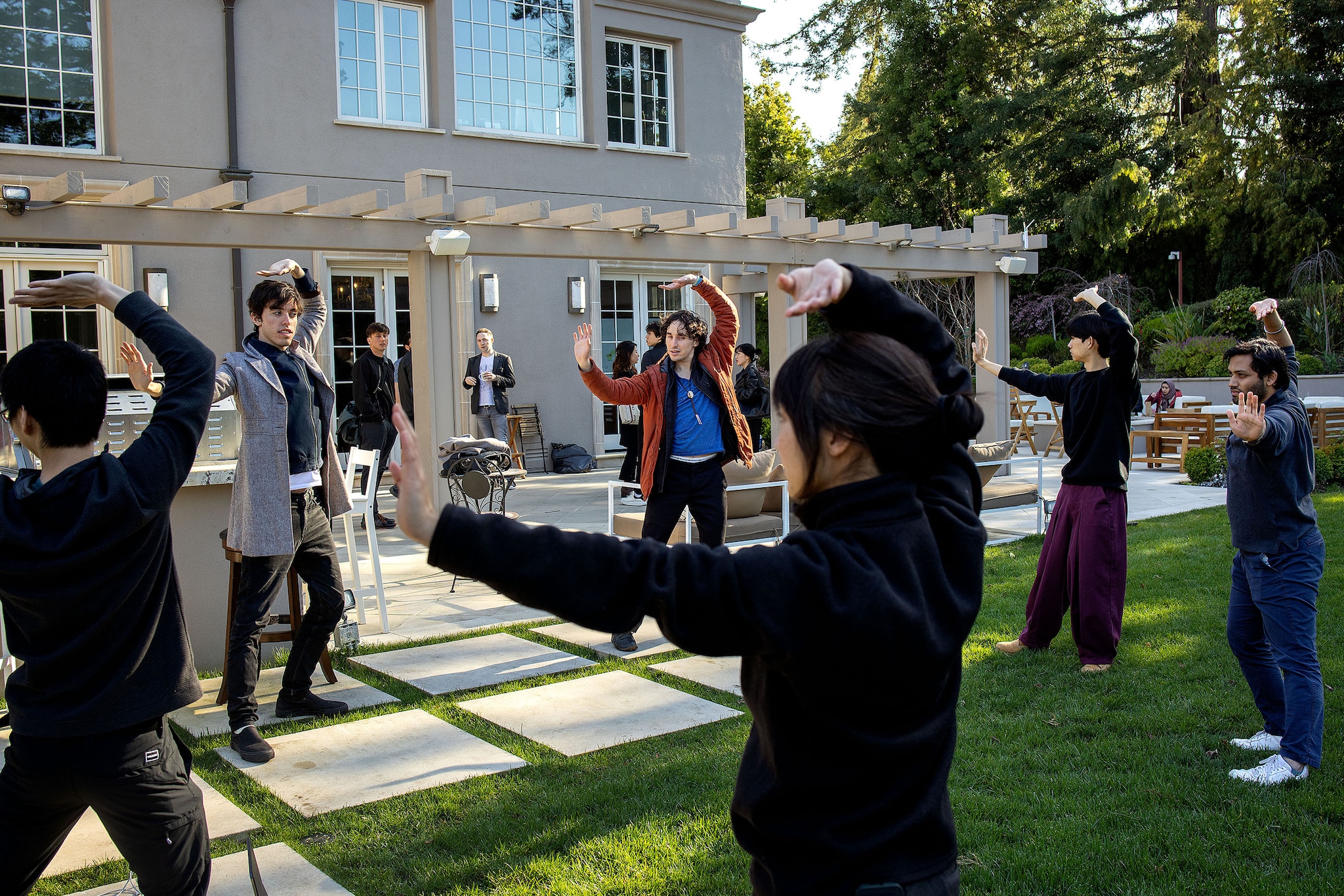 EXTRA: Hackathons are big networking opportunities, with participants frequently meeting people who go on to become co-founders, teammates, friends, even romantic partners. // Jacob Cole (center) leads a Qigong session in the backyard as a break for people competing in the hackathon during the AGI House LLM Hackathon at the “AGI House,” a hacker house in Hillsborough, California on March 25, 2023. The one-day hackathon was planned around the release of GPT-4 and drew hundreds of excited attendees. Hackathons are an opportunity for individuals to build something in a set amount of time, testing and refining their skills, but they are also social events. While coding away, people make friends and build community with one another. 
