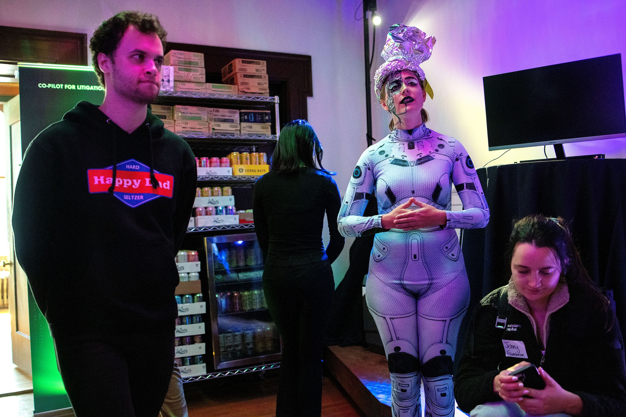 Michaela Carmein (second from right) watches demos while helping out during the HF0 Demo Day where she entertained guests by pretending to be an AI robot named “Guinevere” during the event for the start-up fellowship in San Francisco, Calf., on Tuesday, April 4, 2023. She talked to guests in character throughout the entire event. Carmein’s close friend, Emily Liu, is one of the co-founders of HF0, and she helped her friend create a memorable event with the costume and act. Demo days at other programs can often be routine events with start-ups mostly giving slide deck presentations, but the HF0 team added creative details throughout their demo day to make the event fun for guests.