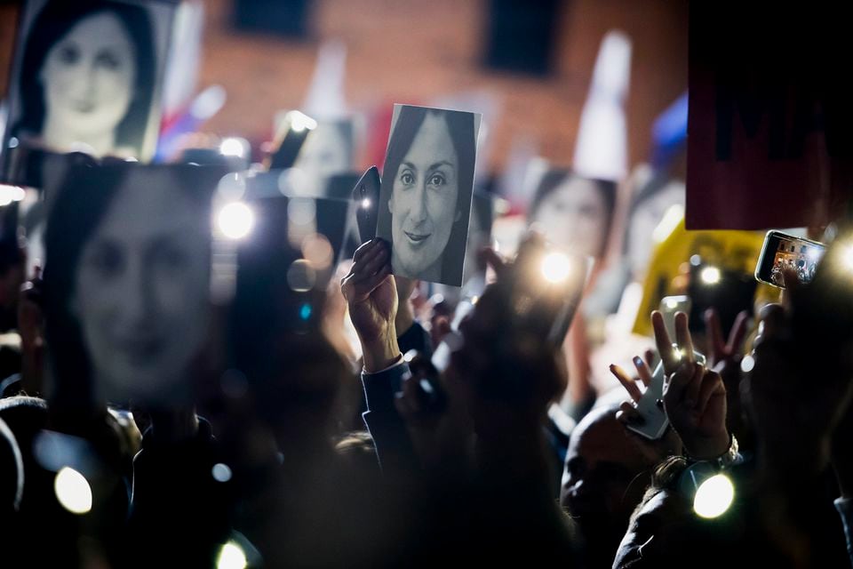 People held pictures of slain journalist Daphne Caruana Galizia as they protested in November 2019 outside the office of the Maltese Prime Minister Joseph Muscat, in Valletta, Malta.  Prosecutors allege she was killed in a contract killing, paid for by a top Maltese businessman with government ties.