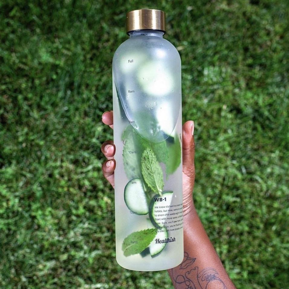 healthish pre launch product water bottle held up against leaves