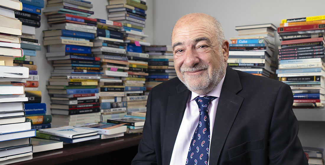 Dr. Sergio Litewka in his office, with books stacked along the walls