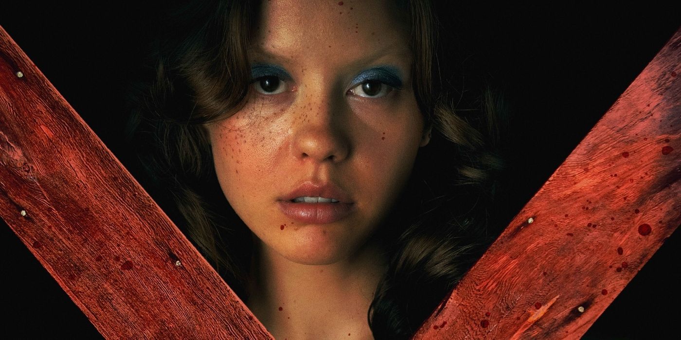 Mia Goth as Maxine in 'X' stands behind a large wooden X