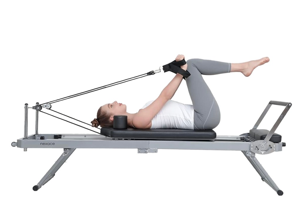 A woman lying on a pilates reformer machine.