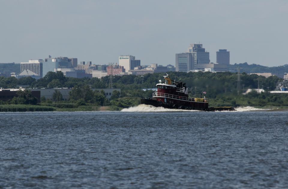 A tugboat heads south on the Delaware River with the Wilmington skyline in the background.