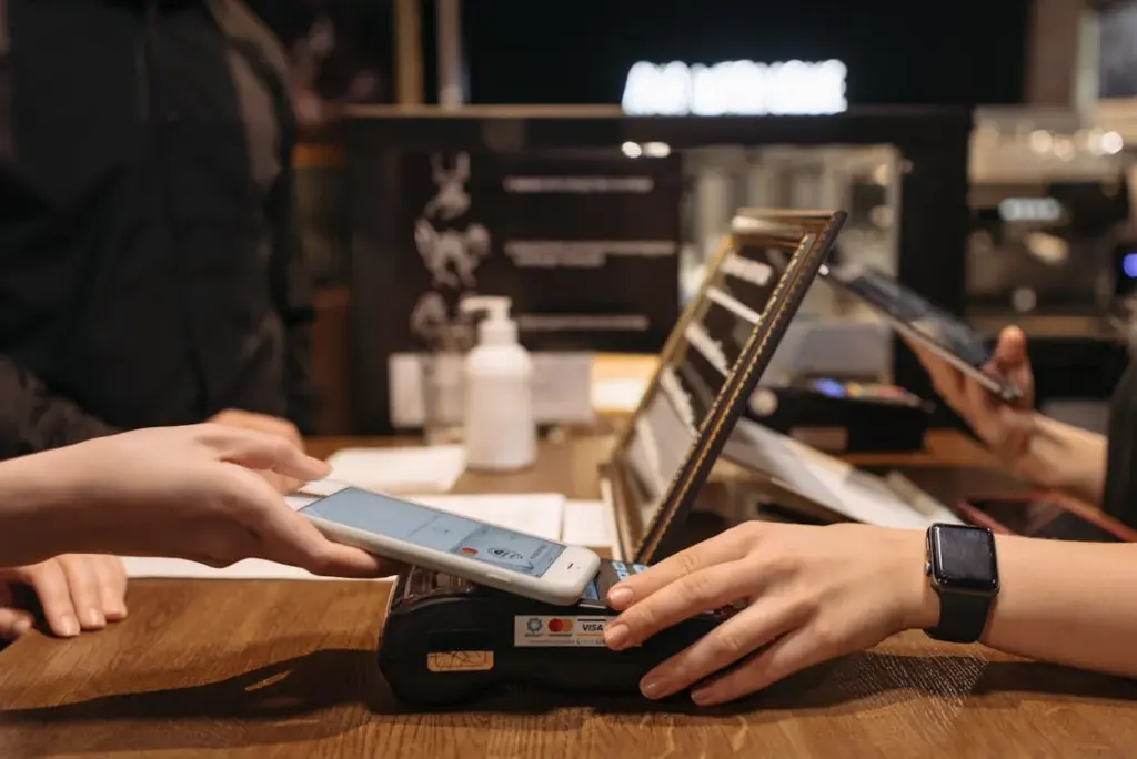 People making contactless payments with smartphones at a counter, politely navigating ways to say no tips on credit card transactions.