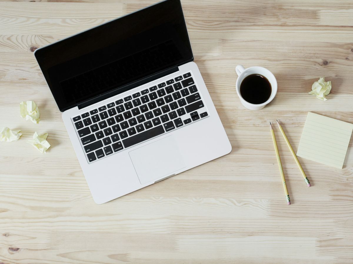 turned off MacBook Pro beside white ceramic mug filled with coffee