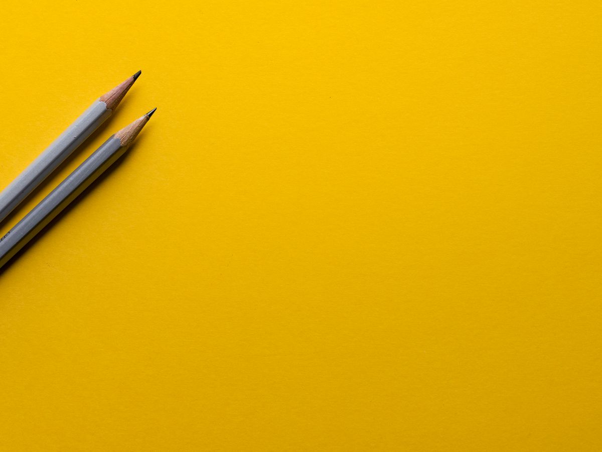 two gray pencils on yellow surface