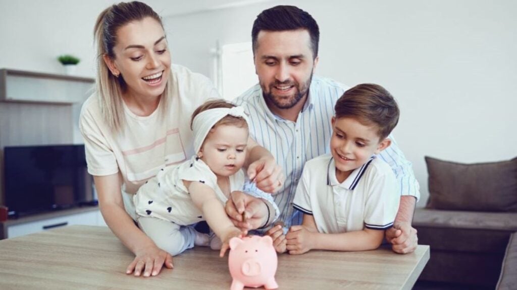 How To Save Money for Kids: Here Are 9 of the Best Ways; Family Adding Money to piggy bank