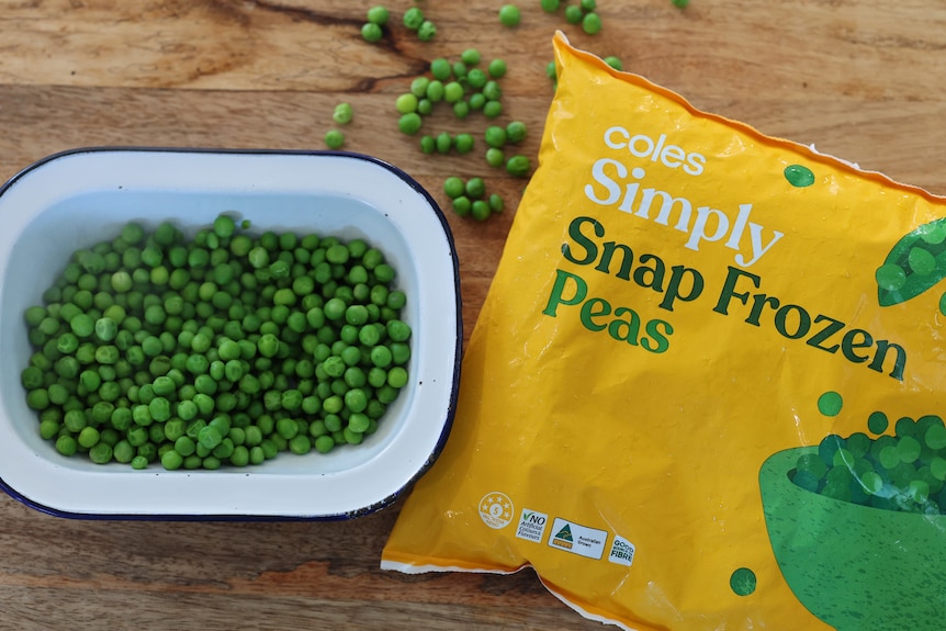 a small tray of cooked pea sit next to a bag of frozen peas