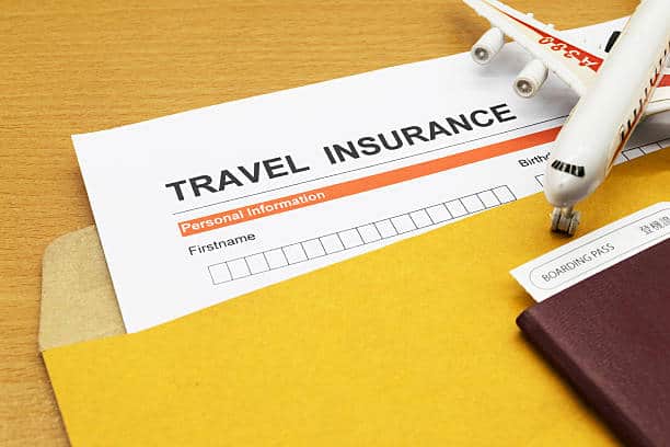 A travel insurance form partially covered by a toy airplane, a yellow folder, and a passport with a boarding pass.