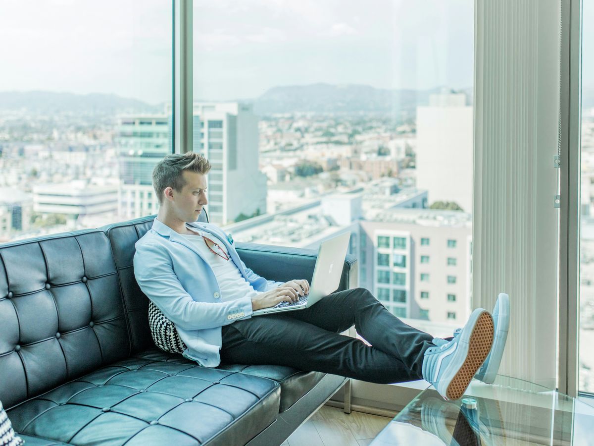 man sitting on sofa while using laptop