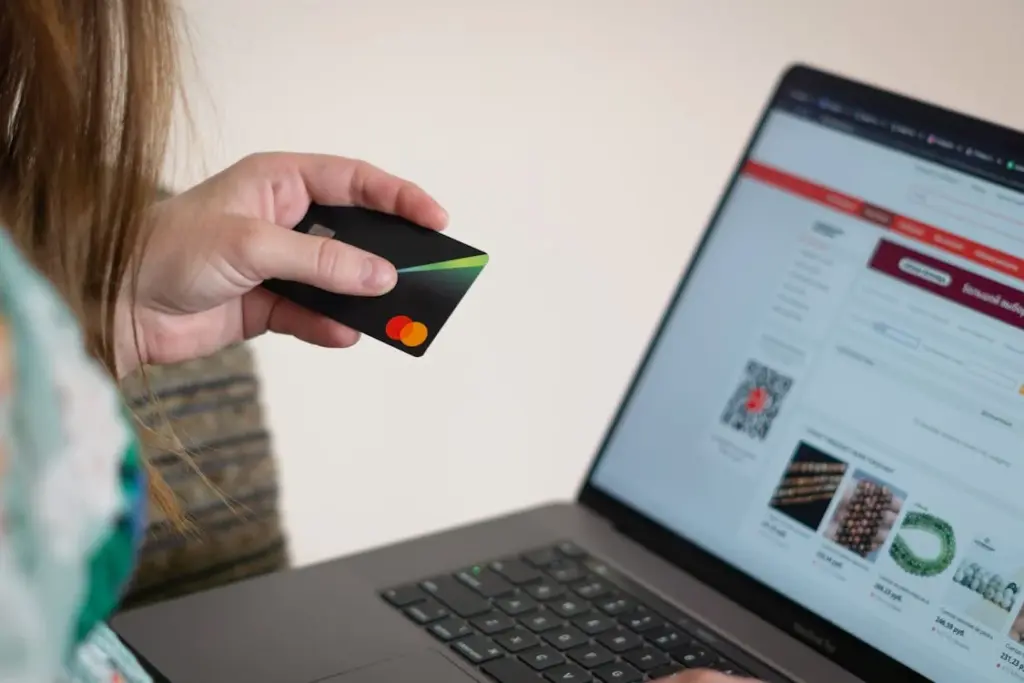 Person holding a credit card while using a laptop to browse an online store's website.