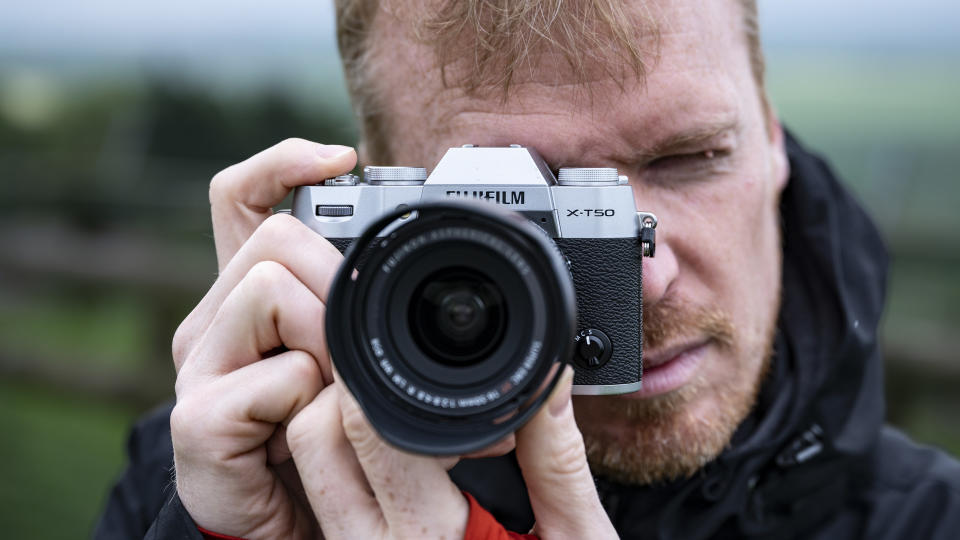  Photographer holding the Fujifilm X-T50 camera up to their eye. 