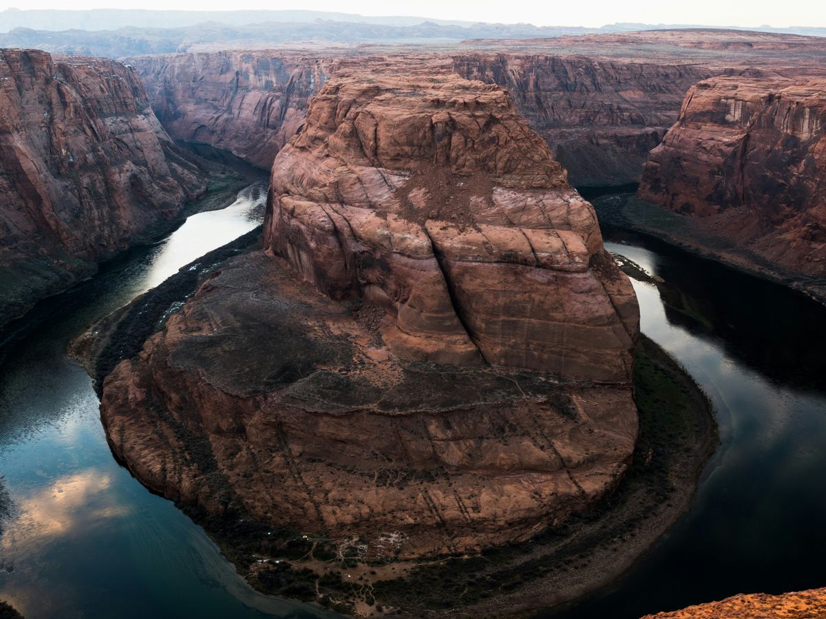 photo of brown buttes surrounded with river