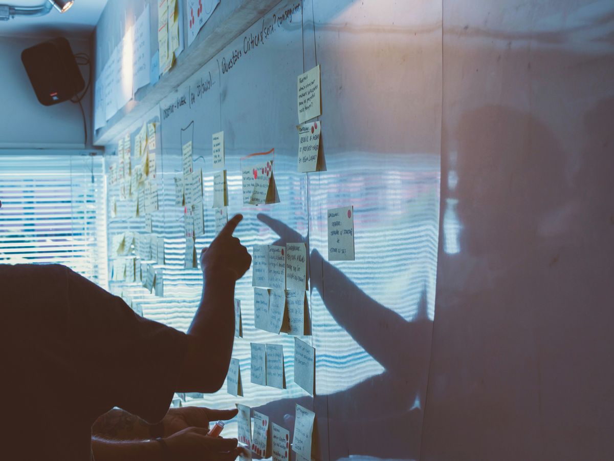 person pointing white paper on wall