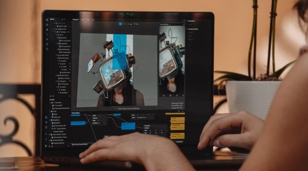 Person working on a laptop with a 3D modeling software displaying a virtual reality headset design.