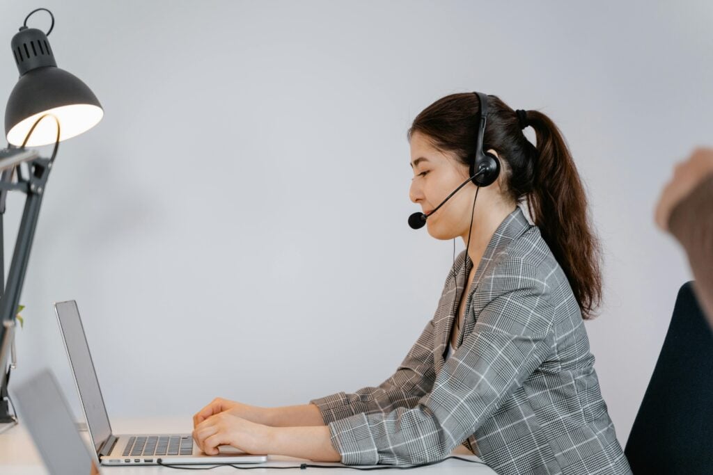 A person wearing a headset sits at a desk, using a laptop in a professional office setting.