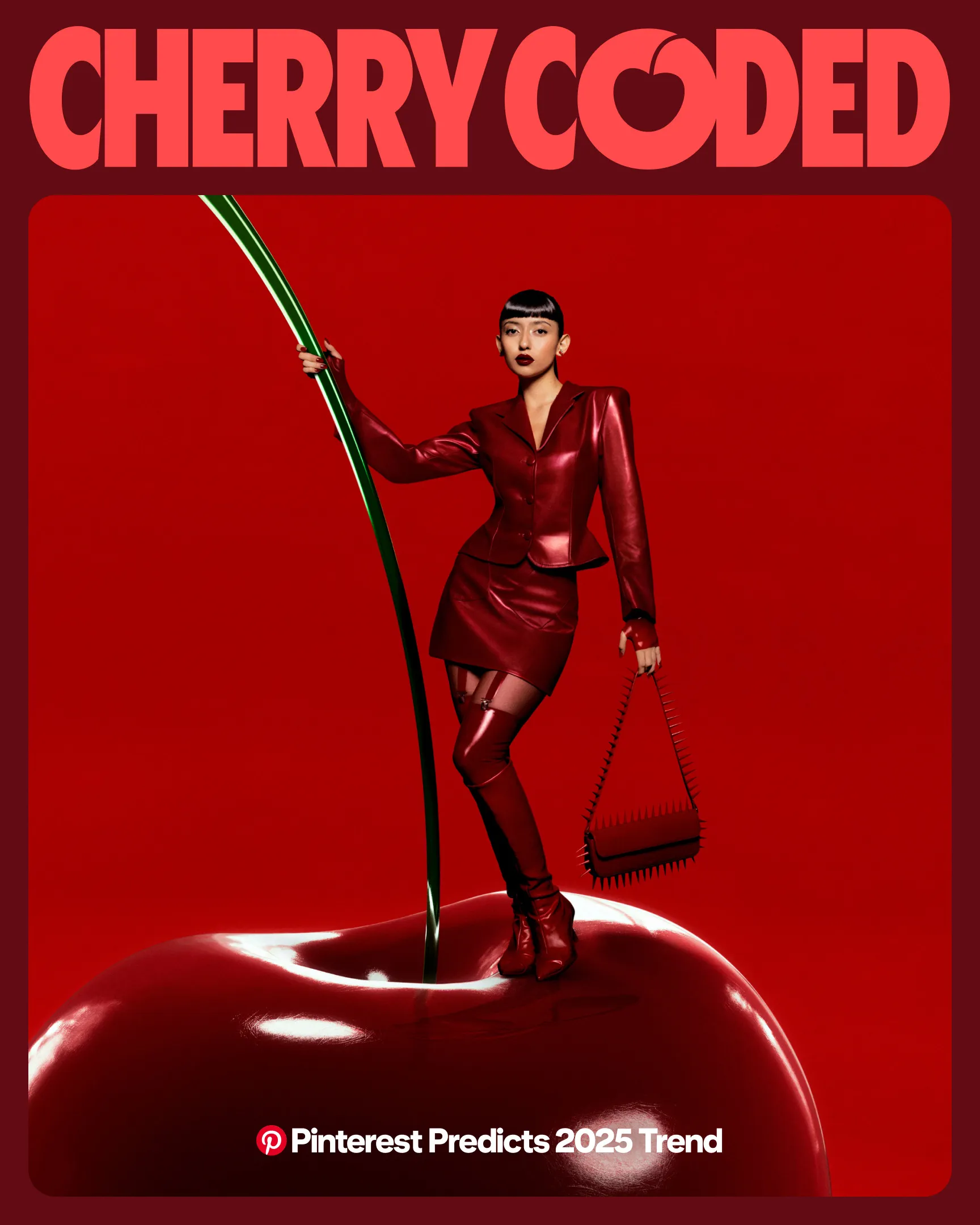 A woman with sleek black hair, dark red lipstick and a head-to-toe red leather outfit poses on top of a giant cherry